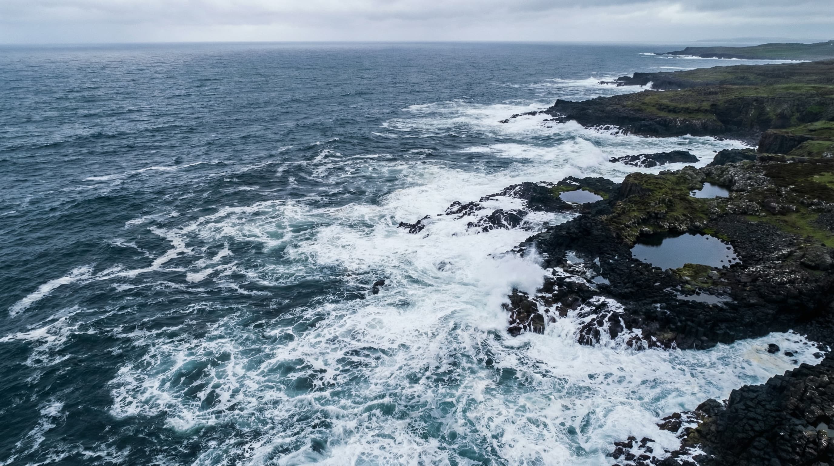 Coarse Atlantic sea salt crystals in a shallow stone pool with the ocean visible in the background